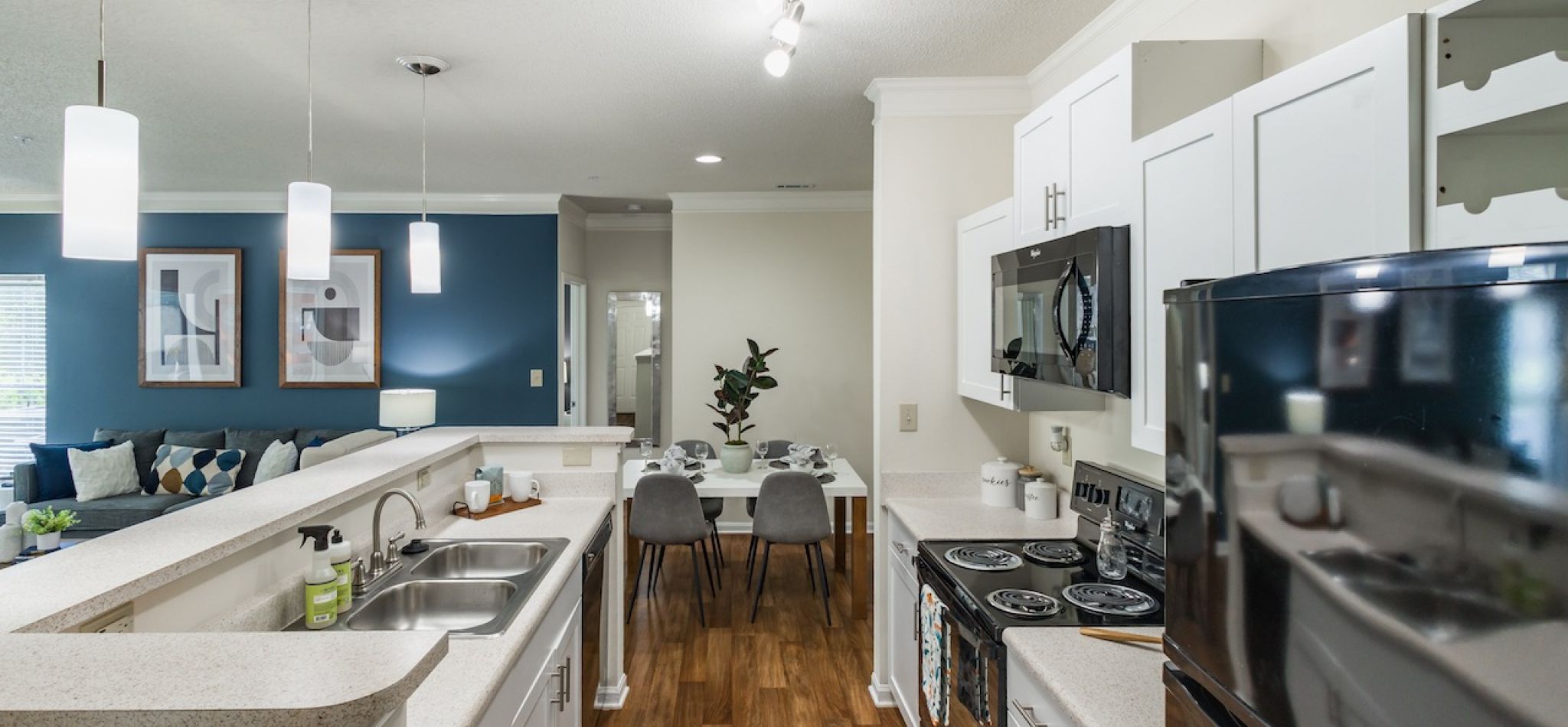 Hawthorne at Main apartment kitchen interior with kitchen island, sleek black appliances, and hardwood inspired flooring
